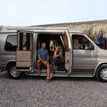 Couple sits in side door of camper van