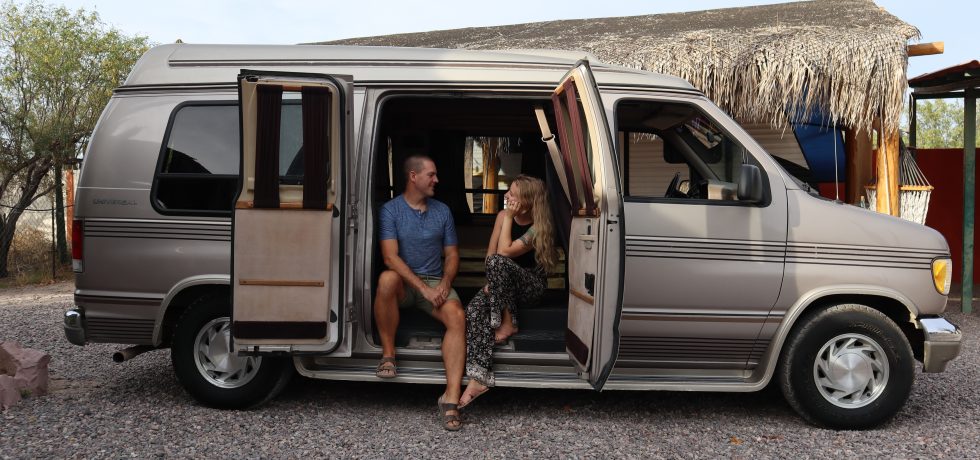 Couple sits in side door of camper van