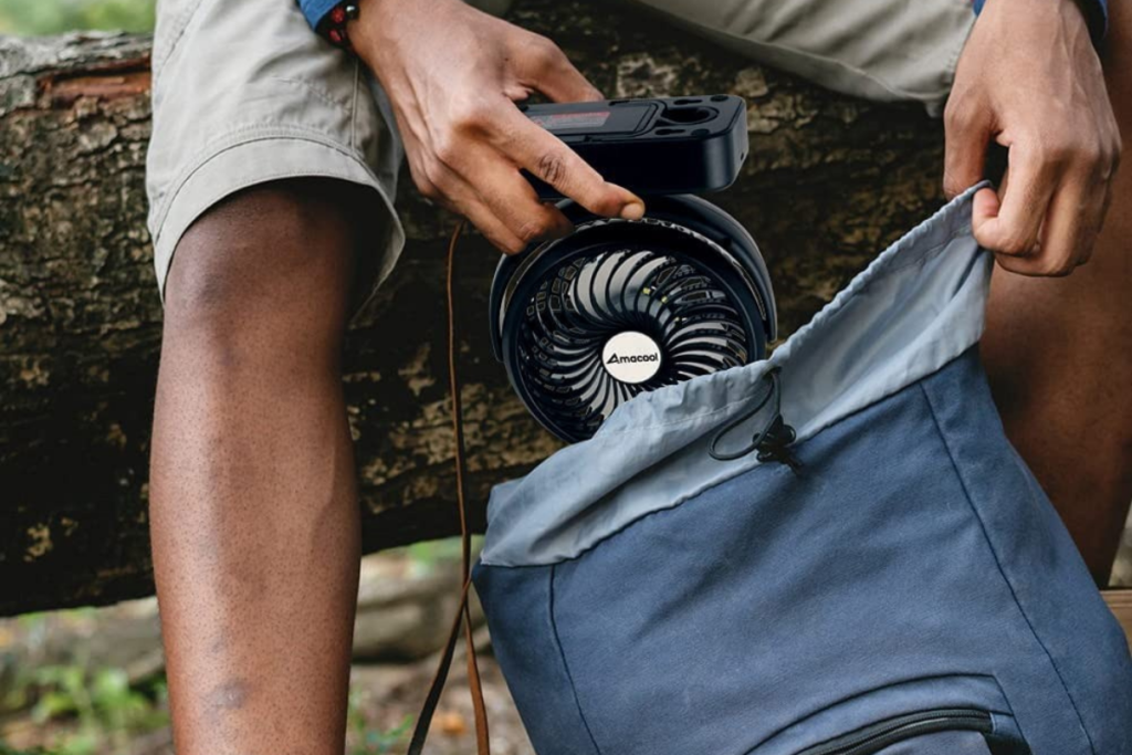 Man putting the Amacool portable camping fan into a backpack