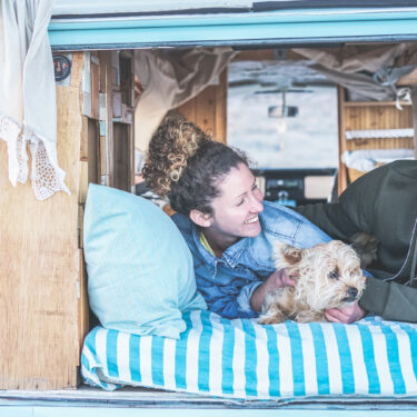 smiling couple laying in back of van conversion with dog