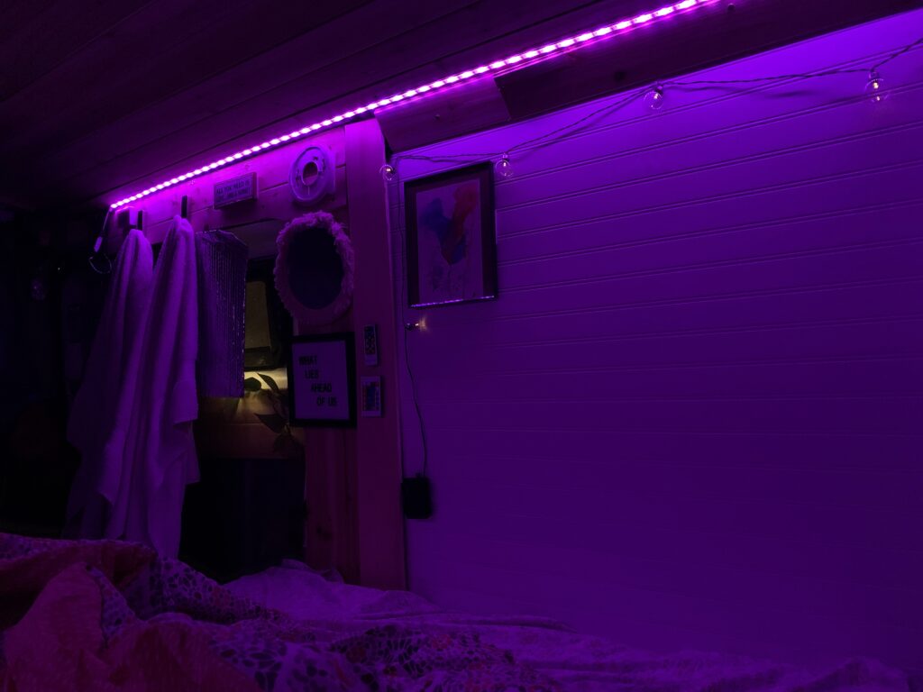 The interior of a stealth camper van with dark purple LED lights.