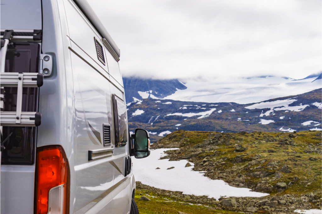 Camper van parked beside rocky snow covered Mountain area - living in a camper van 