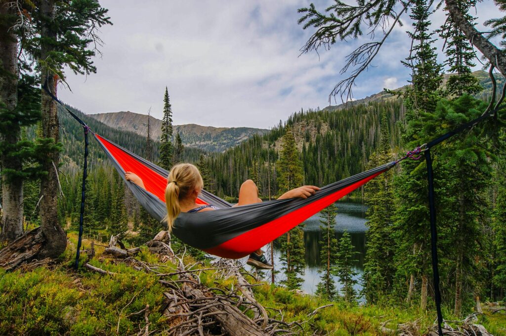Woman laying in a red hammock overlooking a valley