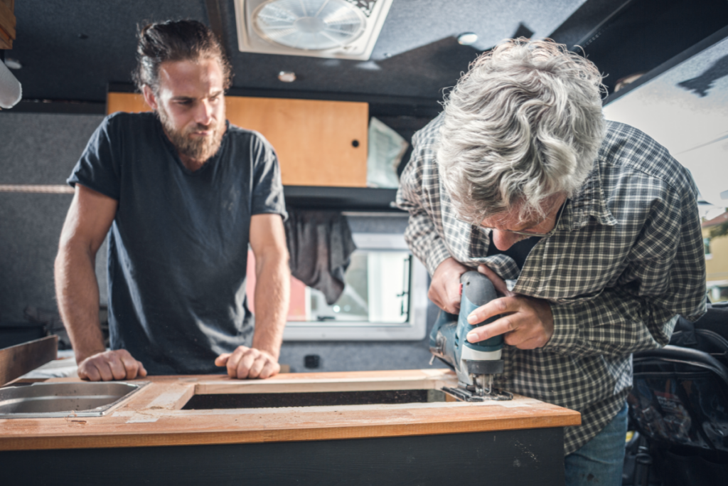 An adult father and son working on a DIY campervan conversion