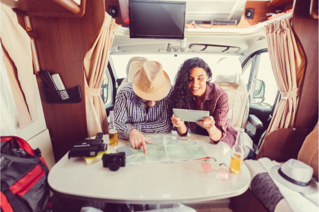 A man and a woman sit at the table in their campervan
