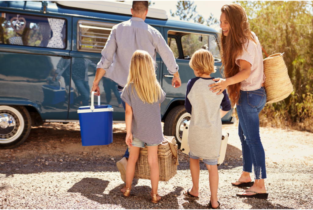 A family of four walking up to a camper van