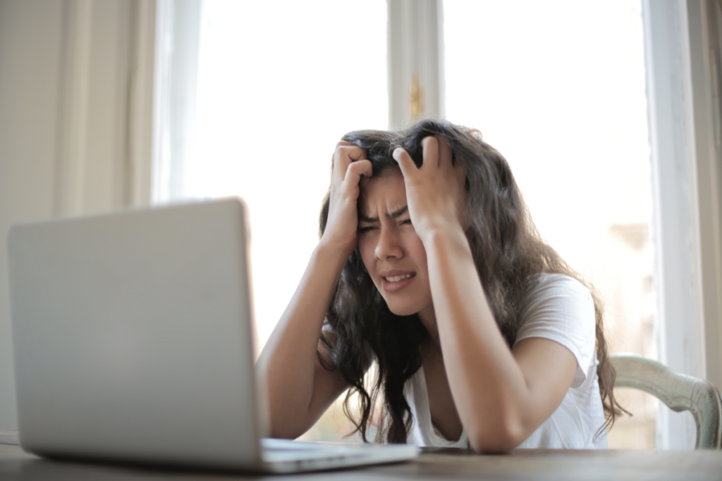 A woman showing extreme frustration while looking at a laptop