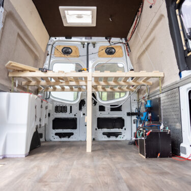 Interior of a van conversion in progress showing the wooden bedframe