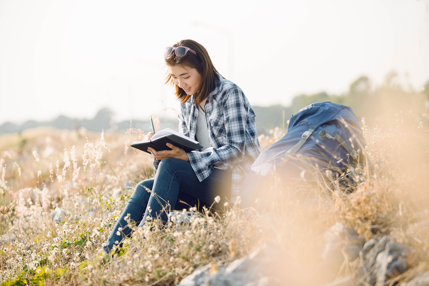 Person writing In a travel journal in a field.