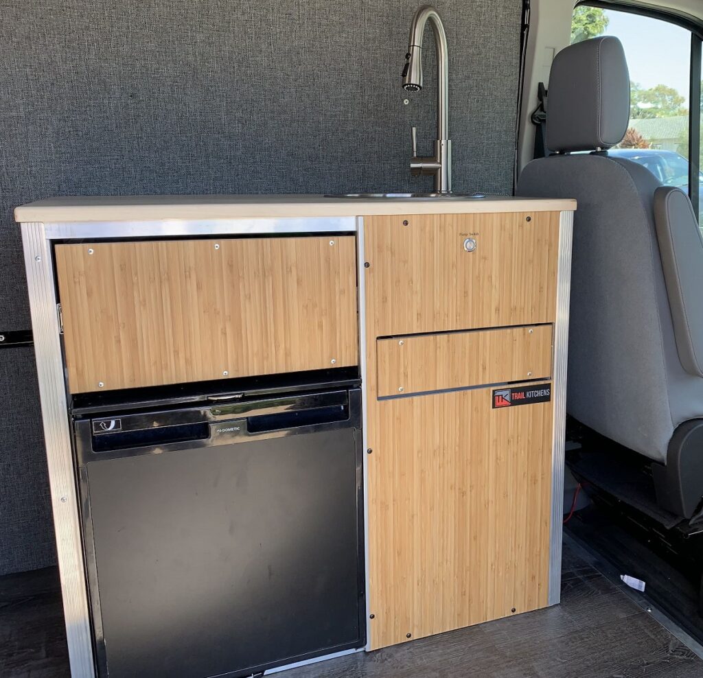 A kitchen and water system from Trail Kitchens inside of a camper van. 