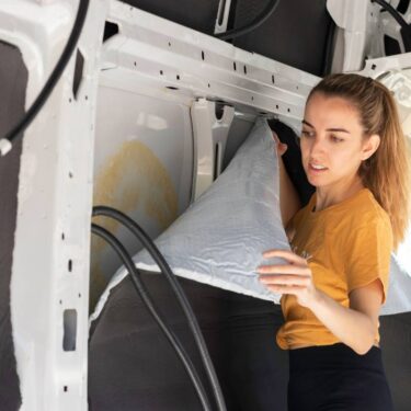 Woman applying van insulation the inside of a camper van