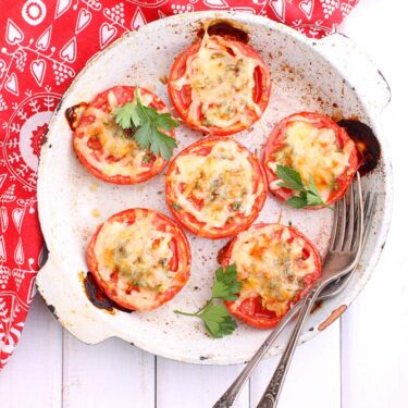 Baked tomatoes with pizza toppings and cheese on top.