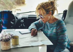 Woman charting van route with paper map, a useful van life must-have
