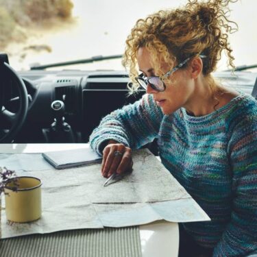 Woman charting van route with paper map, a useful van life must-have