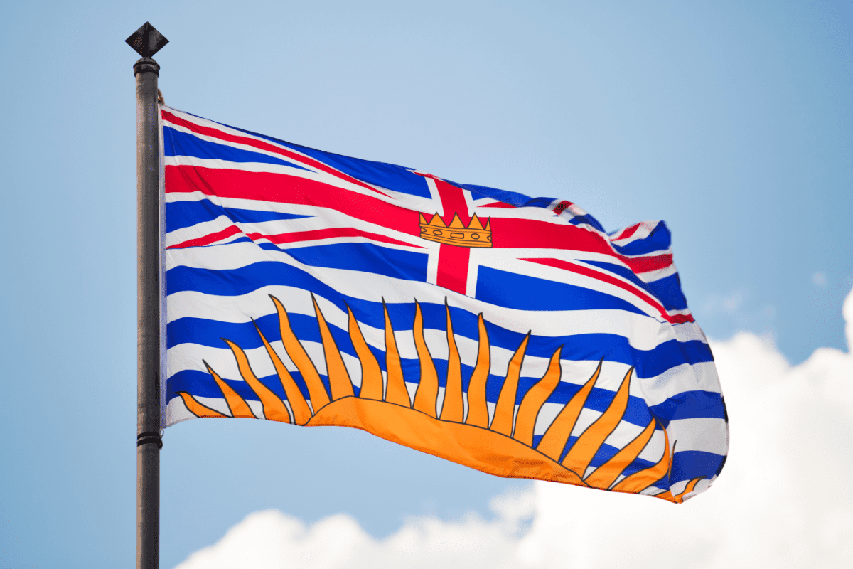The flag of British Columbia flying against a blue sky
