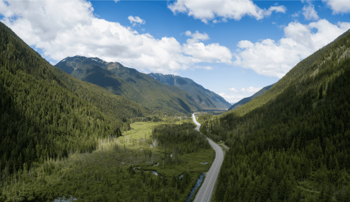 An aerial shot of a highway running through a forest in British Columbia