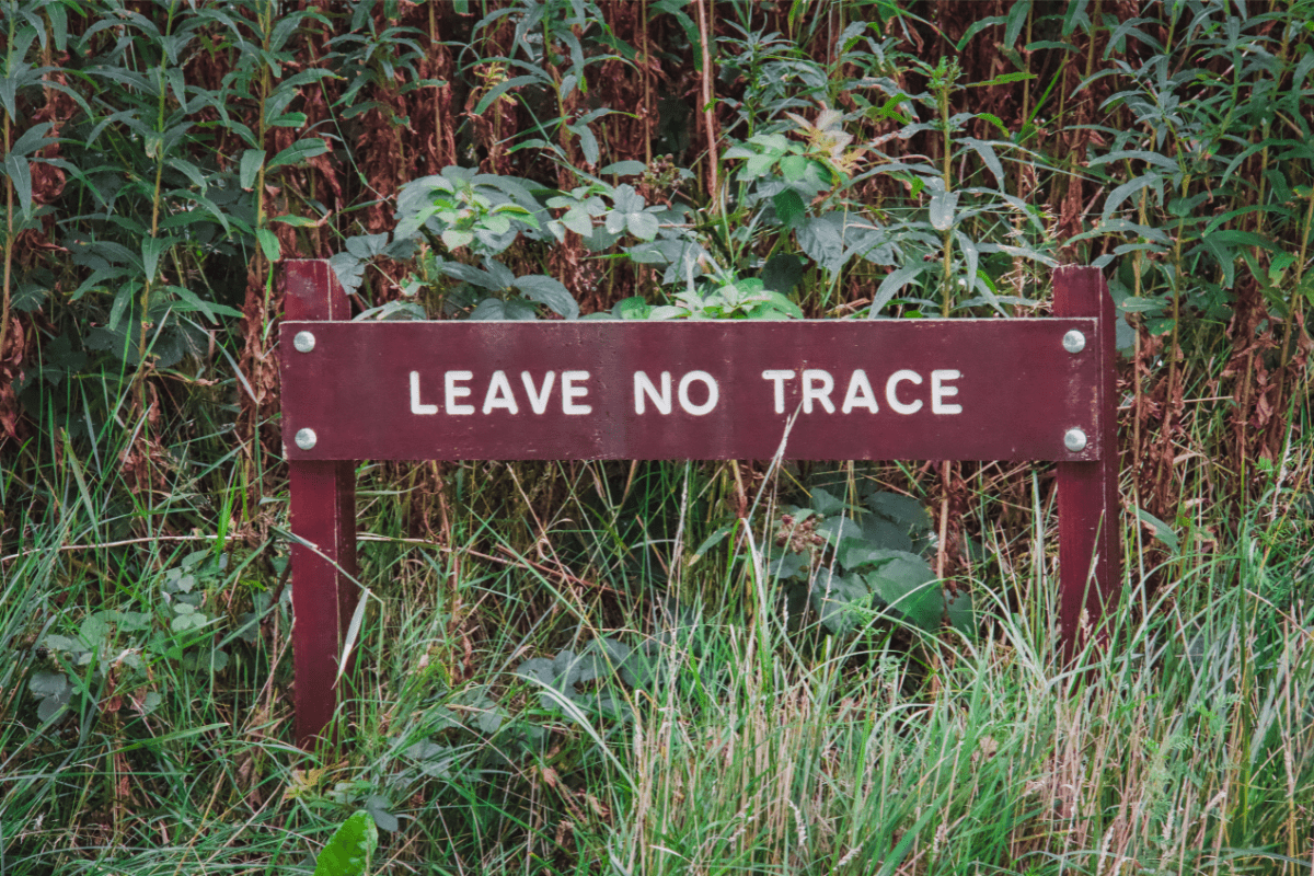A wooden sign reading “leave no trace” surrounded by foliage