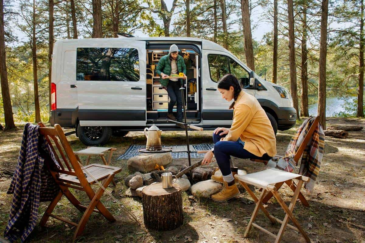A couple camping in front of their 2023 Ford Transit Trail Van