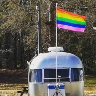 Airstream parked with a gay flag flying overhead