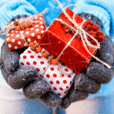 Hand holding gifts in the snow.