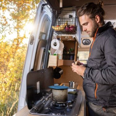 Man in the kitchen area of his Ford Transit van conversion