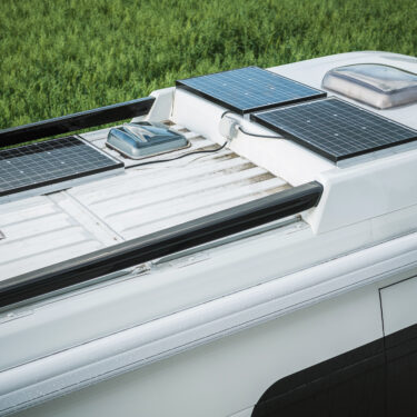 Close view of parked camper van with three panel solar setup on top of roof.