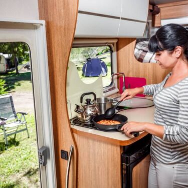 Woman cooking on a stove in a camper van