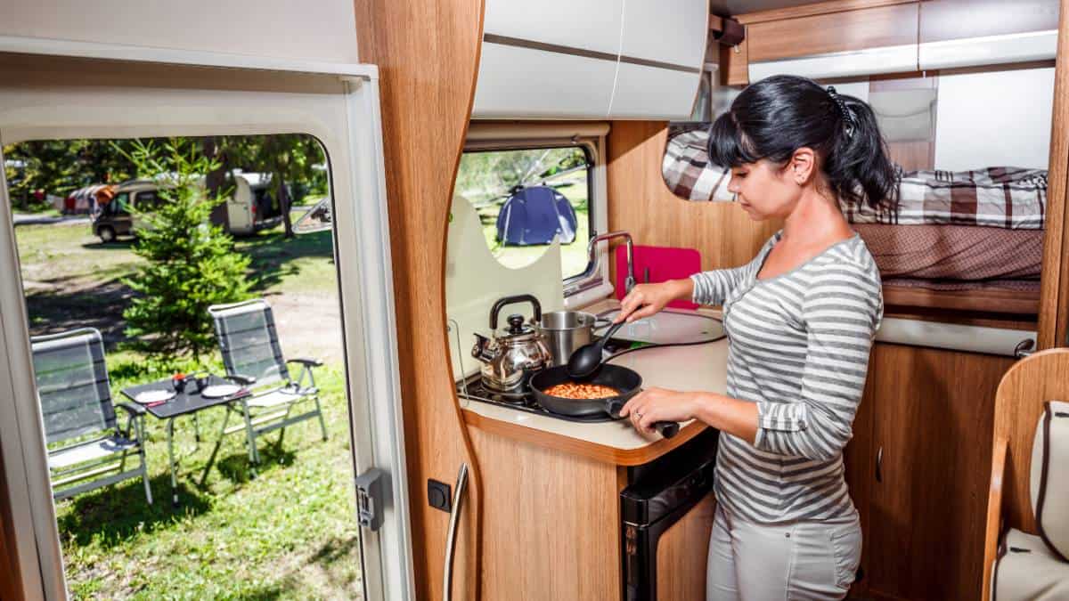 Woman cooking on a stove in a camper van