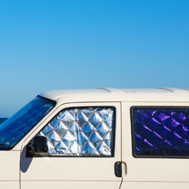 white campervan with thermal window covers with sea in the background