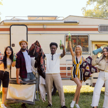 A group of cheerful friends embarking on a road trip to spring festivals in their camper.