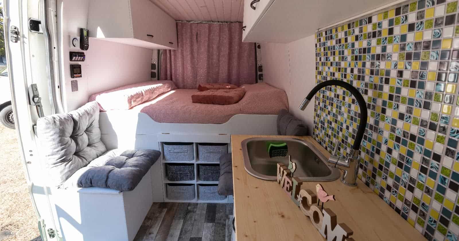 interior of van conversion displaying bed, bench and kitchen counter with neat and tidy campervan storage cubbies