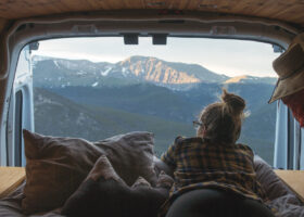 Woman in a camper van enjoying the high altitude mountain view.