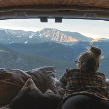 Woman in a camper van enjoying the high altitude mountain view.