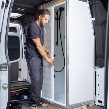 Man installing a camper shower room inside a van