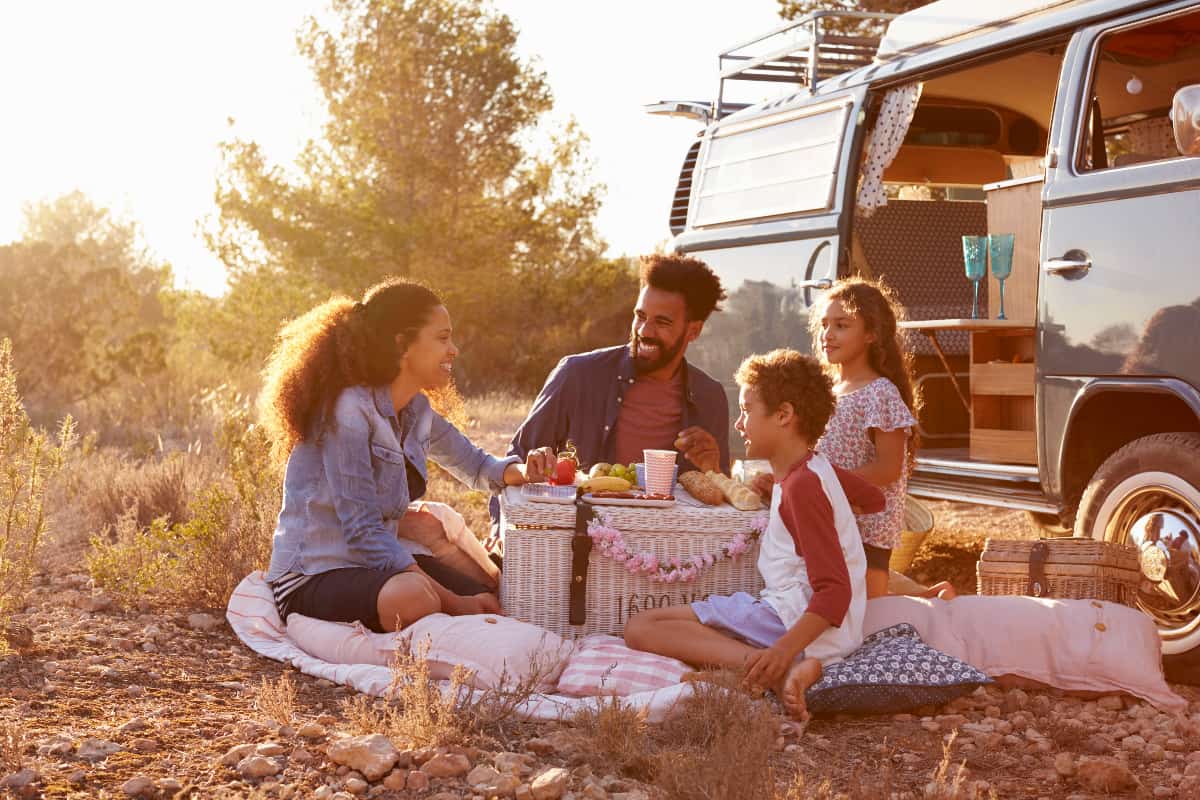 Family-Mom, Dad, and young son and daughter having a picnic beside their camper van