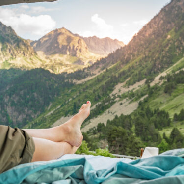 View of the legs of a woman inside a van at sunset, relaxing for her well-being and mental health