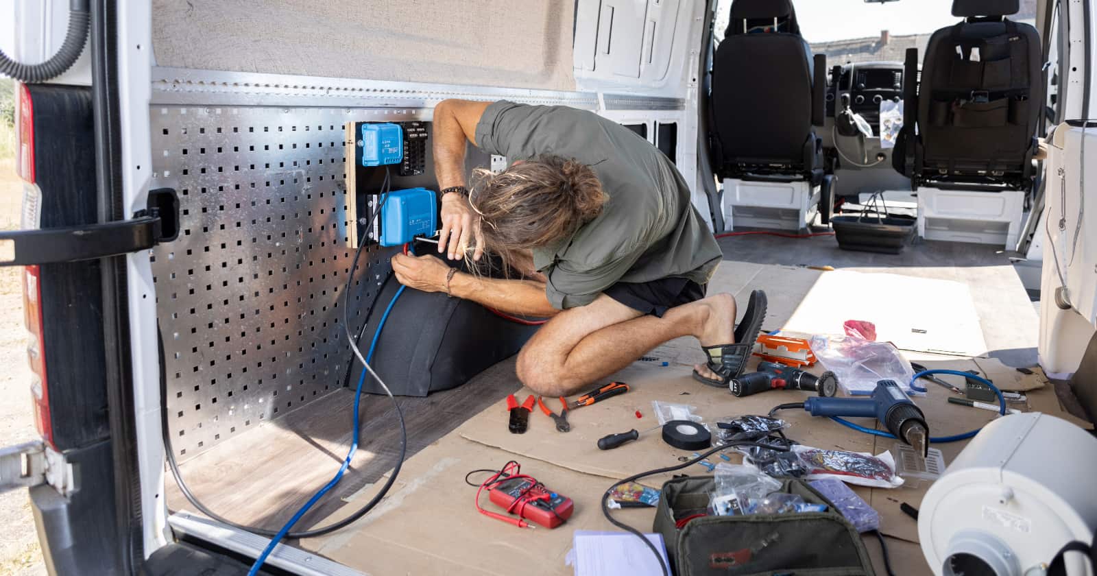 Man wiring electrical components inside a van.