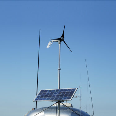 Camping in the desert with wind turbine and solar panels for converting energy from the sun to electricity.
