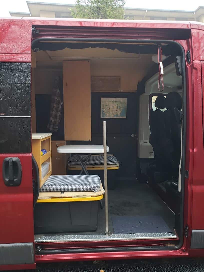 Inside van showing custom seats, portable dining table and handle bar.