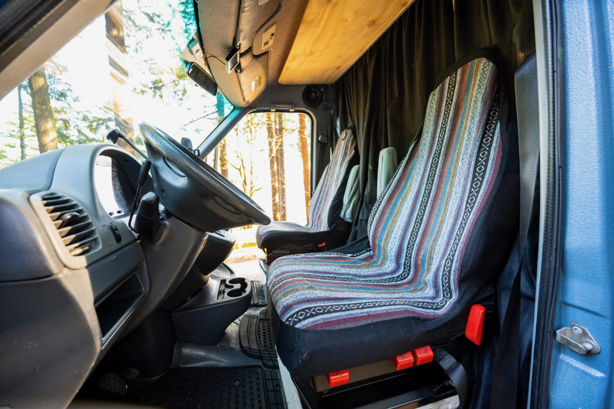 Driver's seat and passenger seat in a converted van, featuring custom patterned upholstery that adds a personal touch to the vehicle's interior.