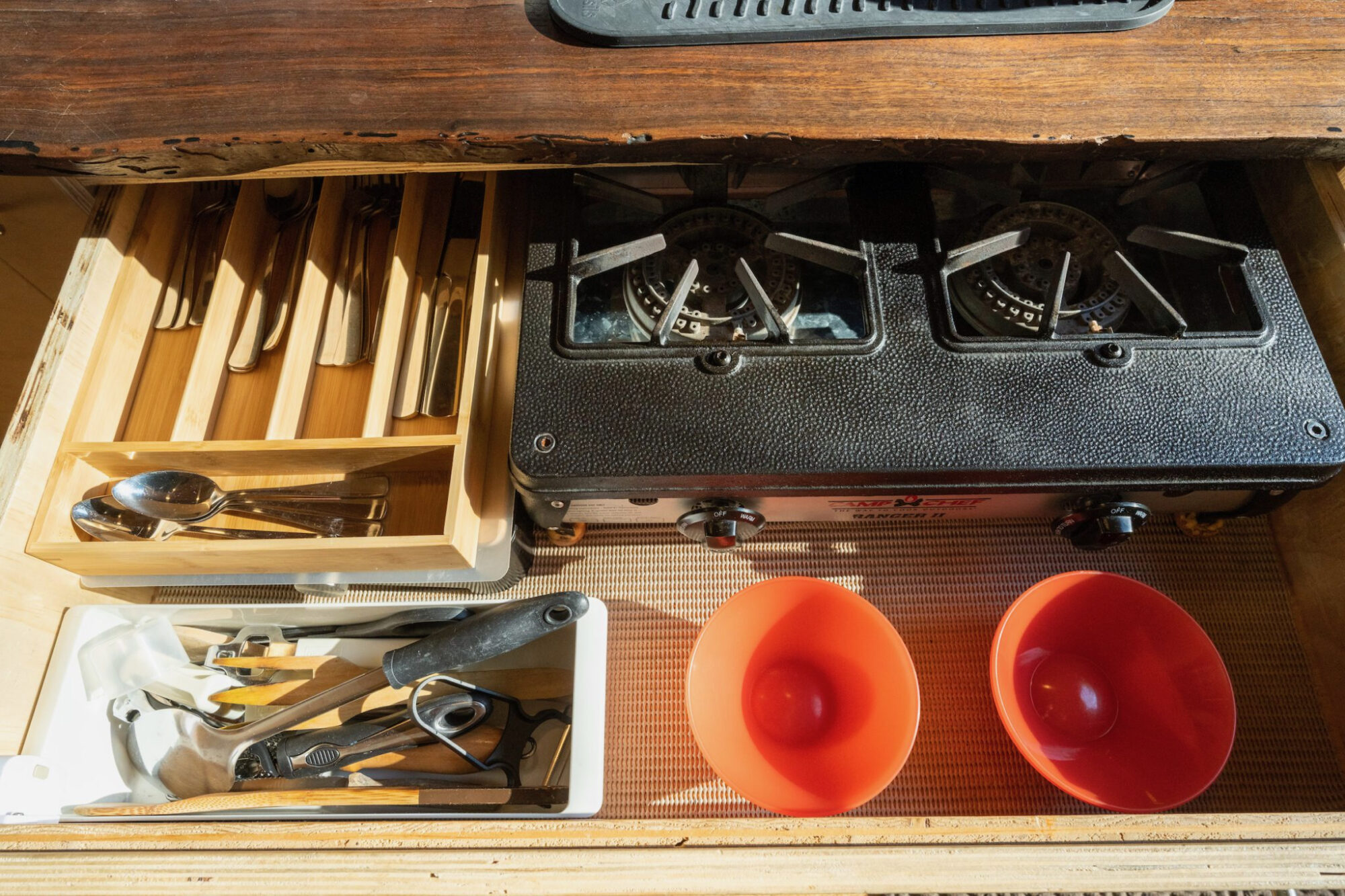 Utensils and a propane burner in a drawer.